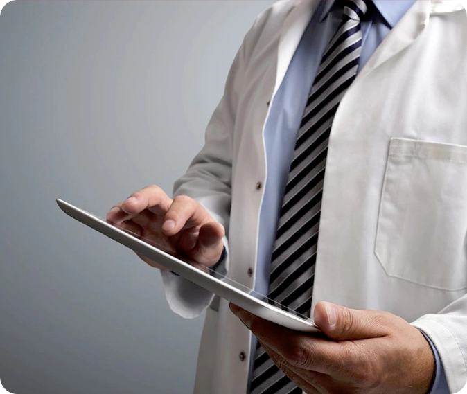 A man in white lab coat and tie using a tablet.