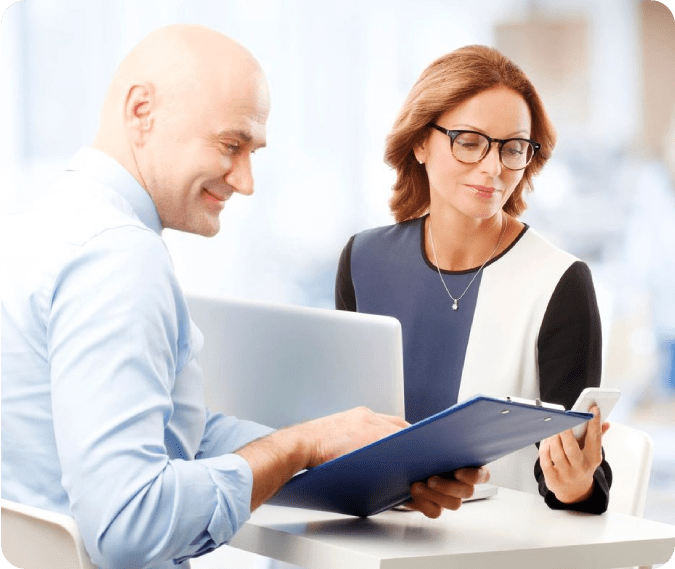 A man and woman sitting at a table with papers.